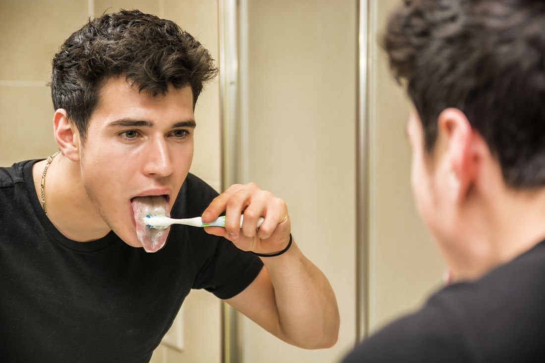 Man brushing his tongue in the morning.